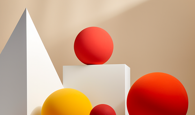 Red and yellow 3D spheres sitting amongst a white pyramid and cube.